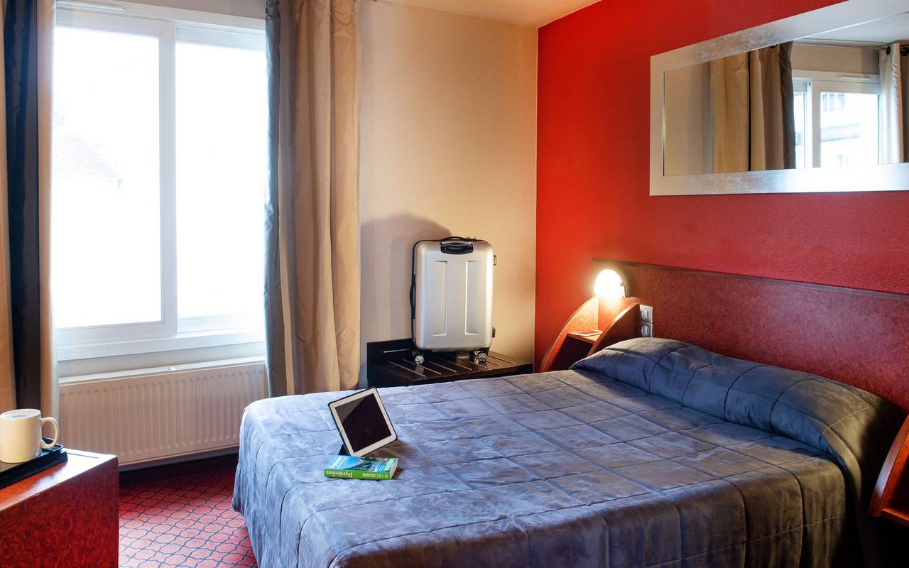 Single room with Ipad on the bed, a desk and large window, hotel occitanie, Hotel La Solitude.